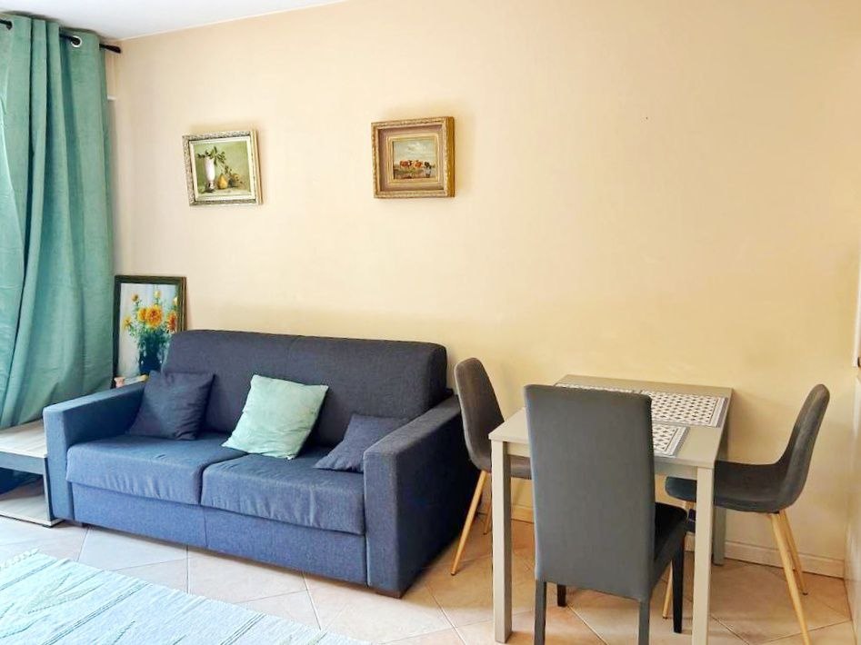 Living room with sofa bed, dining table and light from the terrace