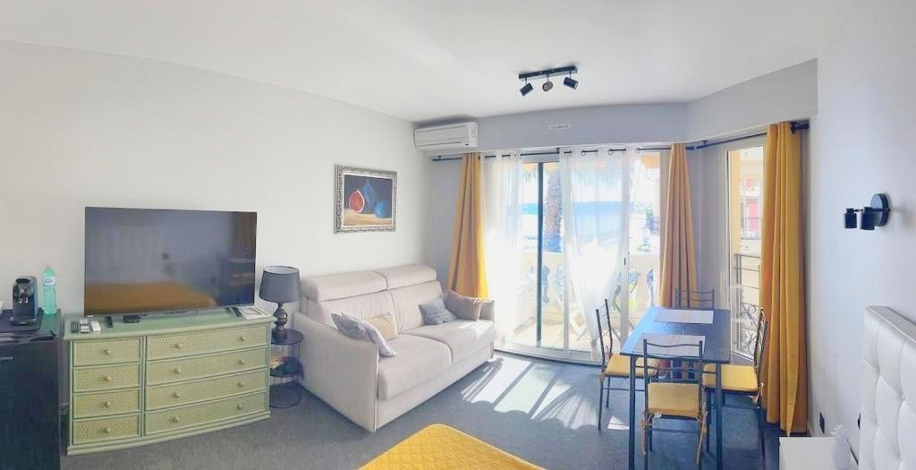 Bright open-plan studio with sofa, dining table, bed and balcony access