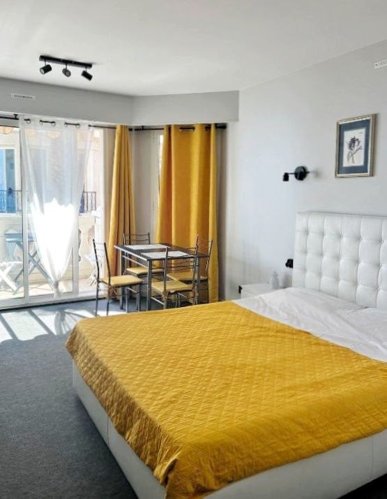 Double bed in a bright studio with dining area and balcony access